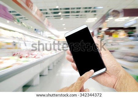 Man asia hand hold and touch screen smart phone,on Blurred defocused background of generic supermarket people walking shopping