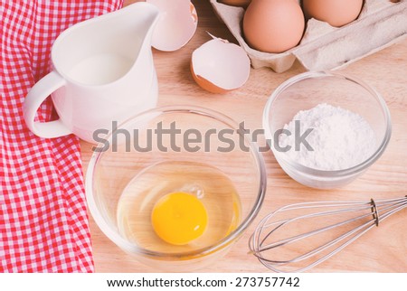 Cookies ingredients. Bowl, flour, eggs, jar of milk, eggbeater,eggshells and red napkin