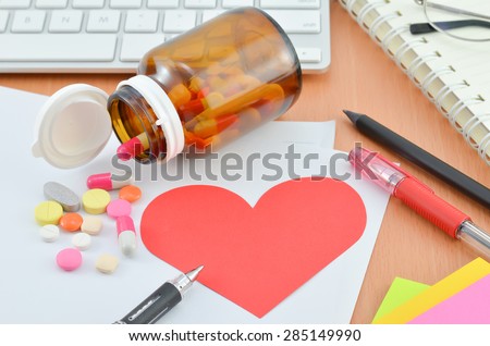 Health Care Concept - Red heart note paper with supplement on computer desk