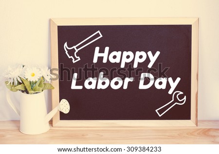 Black board and artificial flower in watering can with vintage color - Happy Labor Day and tool