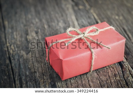 Red box gift with brown rope on old wooden table - Vintage and vignette tone