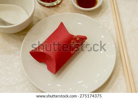 An aerial view of a red gift box place on white plate with others  chinese style eating utensils.