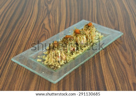 Japanese cuisine of baked salmon maki sushi topped with processed seaweed, roasted same seed and salmon roe.