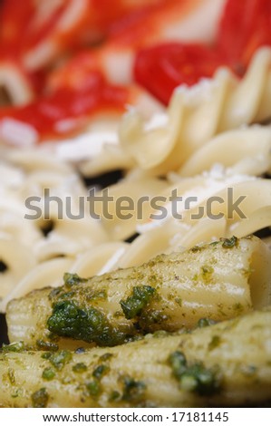 Closeup typical italian pasta arranged with italy flag colors and typical ingredients, pesto, grana, and tomato - shallow dof