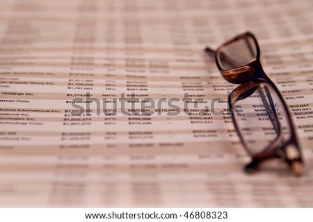 Reading glasses on top of Business page of a financial newspaper