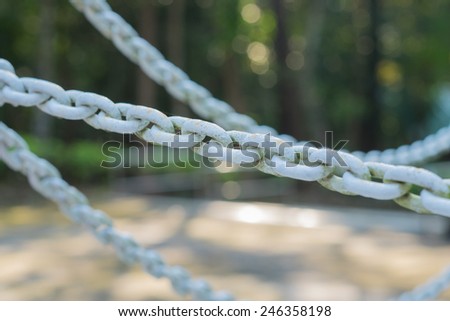 The blurry big chains in a wood lot are exposed to the sun and the rain for a long time.