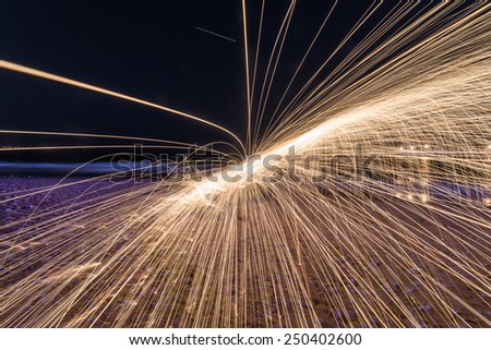 Showers of hot glowing sparks from spinning steel wool at Coney Island Beach, Brooklyn, New York.