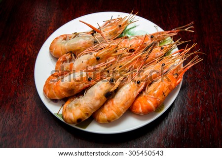 Grilled river shrimps on white plate on wooden background, Thai style food