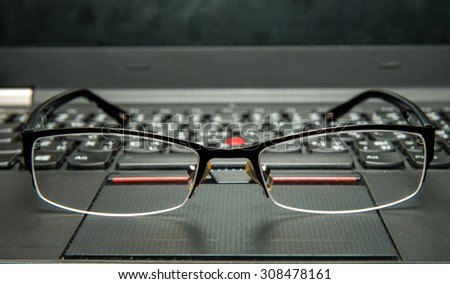 Close up the glasses on laptop computer. Dust on glasses and laptop from office working.(Selective focus on center of glasses and shallow depth of field)