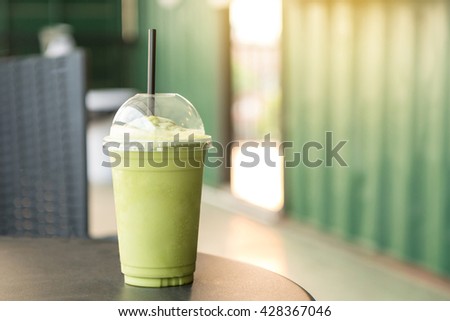 Green tea matcha smoothies in plastic cup. Interior coffee shop. Condensation on a cup (Selective focus and shallow depth of field)