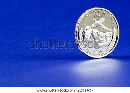 2006 South Dakota State Quarter - reverse side (side with the South Dakota information, not the head). Blue background, reflection in the foreground. Space for text or graphics to the left.