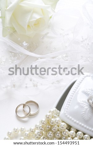 Wedding background with wedding bands, pearls and white rose.