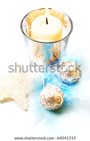 Christmas decoration: creamy candle and star, with silver baubles and feathers.