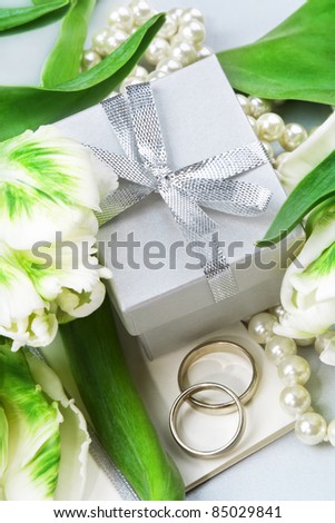 Wedding invitation with wedding rings, pearls, gift box and white tulips. Still life.