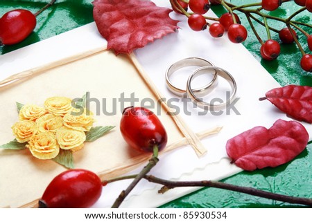 Wedding invitation with wedding rings, decorative wild roses and rowan. Still life.