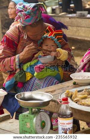 Bac Ha, Vietnam - 17 June 2013 : A flower Hmong feeding her baby at Bac Ha Week end market, North Vietnam.