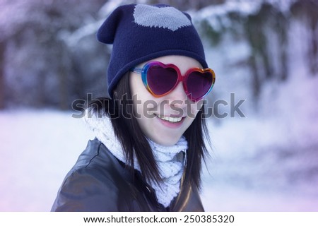 Beautiful young woman smiles in her heart form sunglasses outdoor fashion portrait. / Equipment for Valentine\'s day / Beautiful young woman smiles in her heart form sunglasses outdoor portrait.