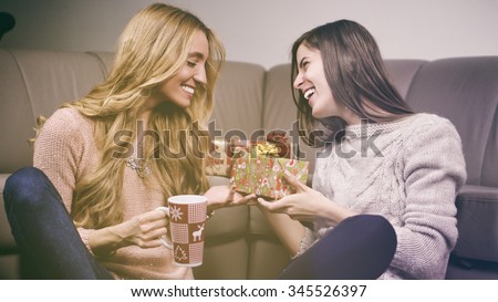 Two women give presents to each other on christmas day. Color effects and custom white balance are used on this picture.