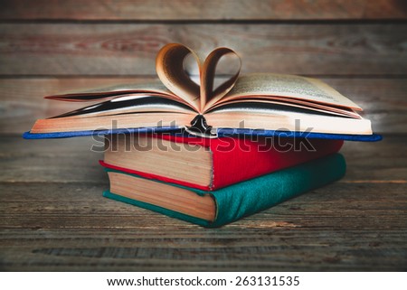 books in the form of heart on a wooden background