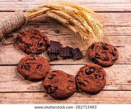Chocolate cookies on white linen napkin on wooden table. Chocolate chip cookies shot on coffee colored cloth, closeup.