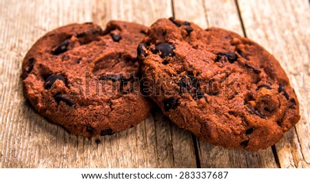 Chocolate cookies on white linen napkin on wooden table. Chocolate chip cookies shot on coffee colored cloth, closeup.