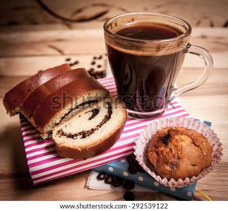 Slice bun with poppy and cup of coffee on wooden table