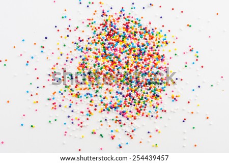 Colorful sprinkles spilled from a jar on white table