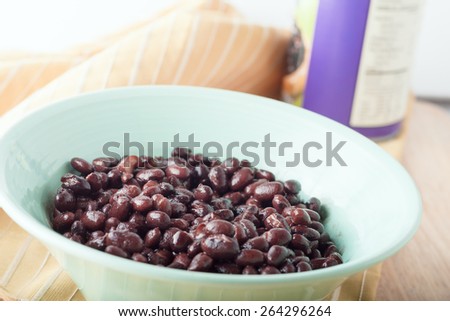 canned black beans in green bowl with orange napkin and the can at the background