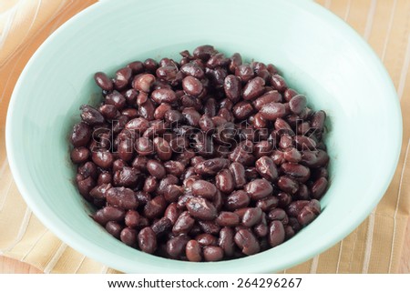 canned black beans in green bowl with orange napkin and the can at the background