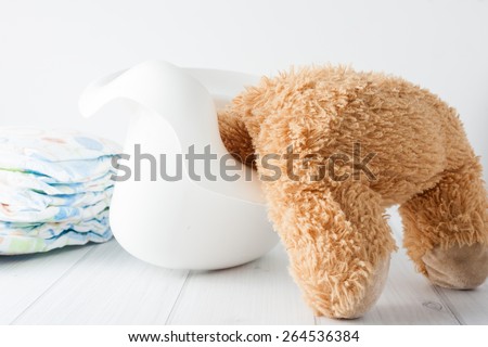 Teddy bear\'s head stuck in the potty - conceptual image representing potty training in young age troubles.