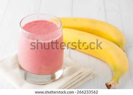 a glass of fresh homemade frozen raspberries and banana smoothie on white background
