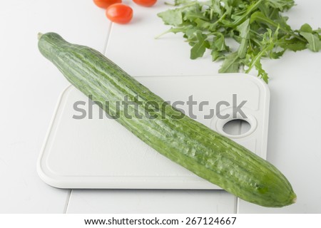 whole organic English cucumber on white chopping board