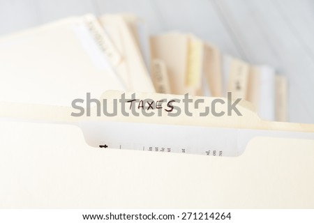 yellow paper folder labeled TAXES containing tax documents of a small business firm