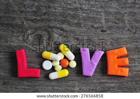 word love is composed of colorful letters with medications instead of the letter o on a wooden Board. February 14 Valentine\'s Day