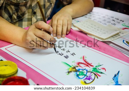 Asian Man writing Chinese Calligraphy on a paper.