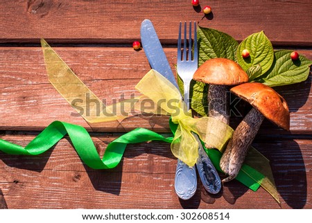 Thanksgiving table setting/ cutlery on the autumn background with autumn leaves and mushrooms with ribbon on wooden background/Thanksgiving holidays background concept