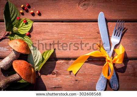 Thanksgiving table setting/ cutlery on the autumn background with autumn leaves and mushrooms with ribbon on wooden background/Thanksgiving holidays background concept