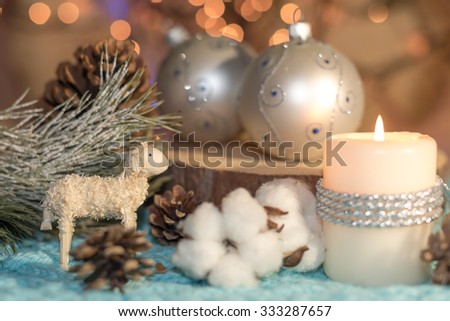 Christmas still life with candle, balls and toy handmade lamb made of wooden sawdust. Focus on the lamb