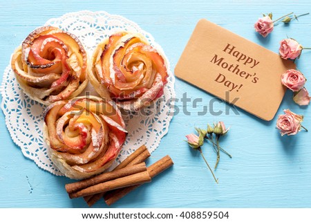 Mothers day card. Homemade Apple rose cake with sugar powder on blue  wooden background. Top view.  Handmade gift for mom/ Mothers day concept card.