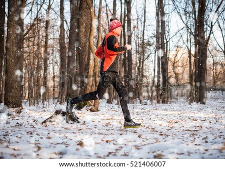 Winter running exercise. Runner jogging in snow. Running man in a city park.