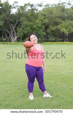 happy fat woman play rugby ball in the park, smiling.