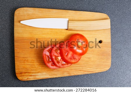 Fresh tomato and white ceramic knife on the kitchen cutting board