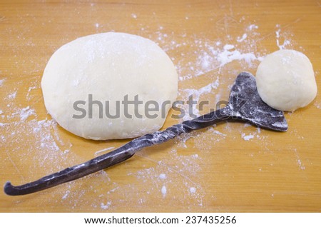 Hand kneaded dough and an old-style dough cutter placed against a wooden board