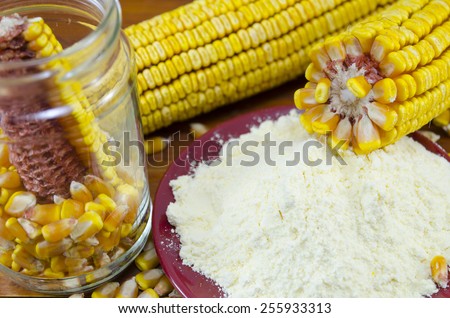 A jar with corn, flour and corn ear on a wooden table