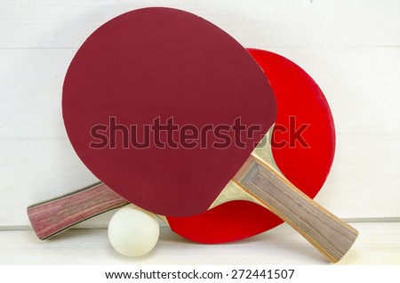 Two table tennis rackets and a ball on a wooden table