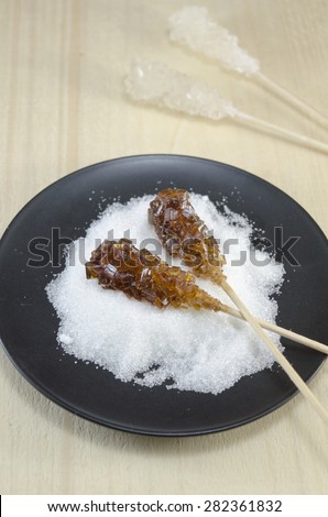 Two sugar sticks containg white and brown sugar in a black plate