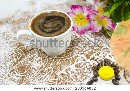 Cup of coffee on a cocoa sprinkled table with flowers