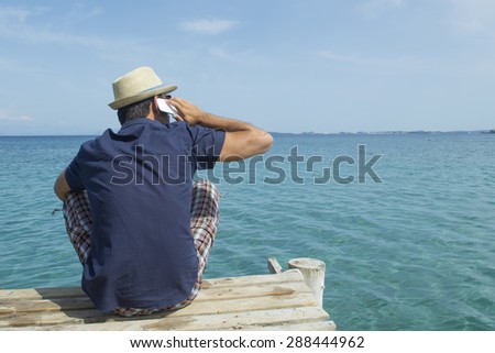 Man talking on his cell phone at the dock at sea