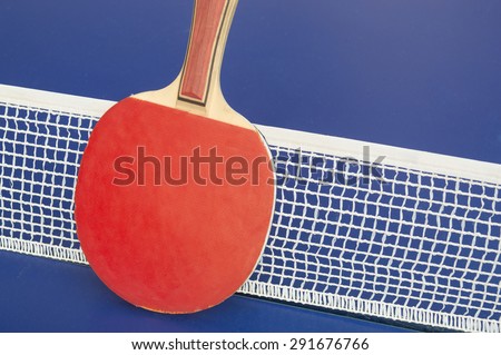 Table tennis racket and net on a blue table tennis table