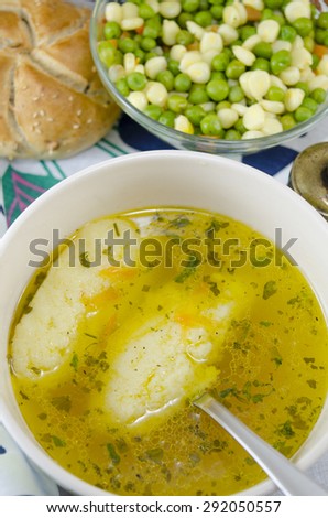 Bowl of homemade soup with noodles and plate of vegetables served with homemade bread